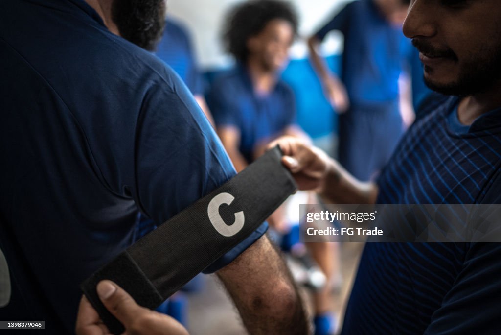 Fußballspieler hilft Mannschaftskapitän beim Anziehen des Armbands