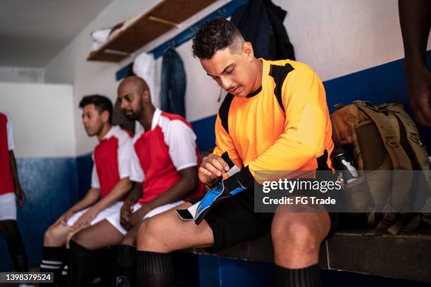 goalie putting on soccer glove before a match in the locker room - luva de guarda redes imagens e fotografias de stock