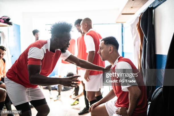 team captain talking to a player before a match in the locker room - team captain stock pictures, royalty-free photos & images