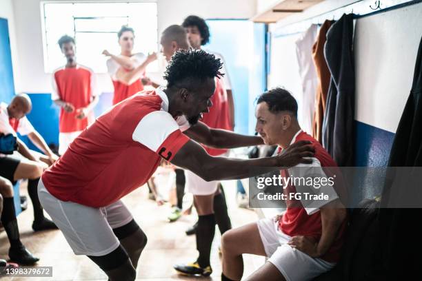 teamkapitän im gespräch mit einem spieler vor einem spiel in der umkleidekabine - mannschaftskapitän stock-fotos und bilder