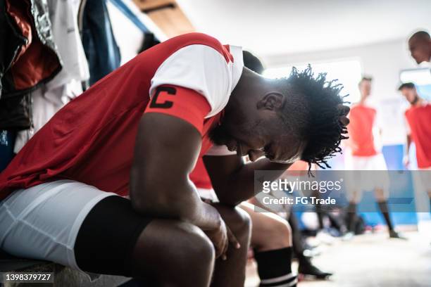 besorgter fußballspieler in der umkleidekabine - soccer injury stock-fotos und bilder