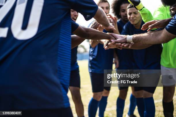 fußballmannschaft, die sich vor einem spiel zusammenkauert - sportliga stock-fotos und bilder