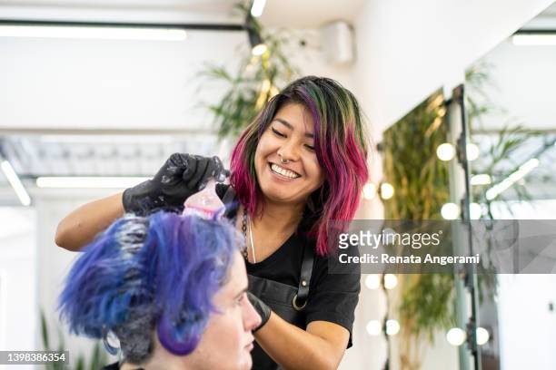 hairdresser dyeing client's hair at hair salon - hair salon stock pictures, royalty-free photos & images