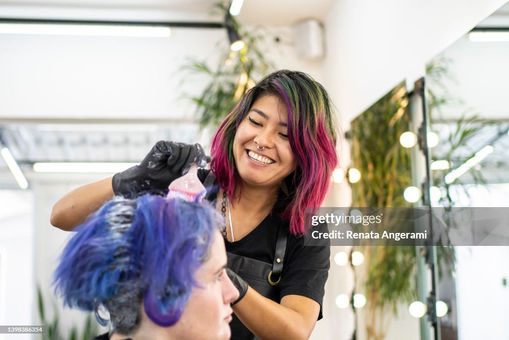 Hairdresser dyeing client's hair at hair salon