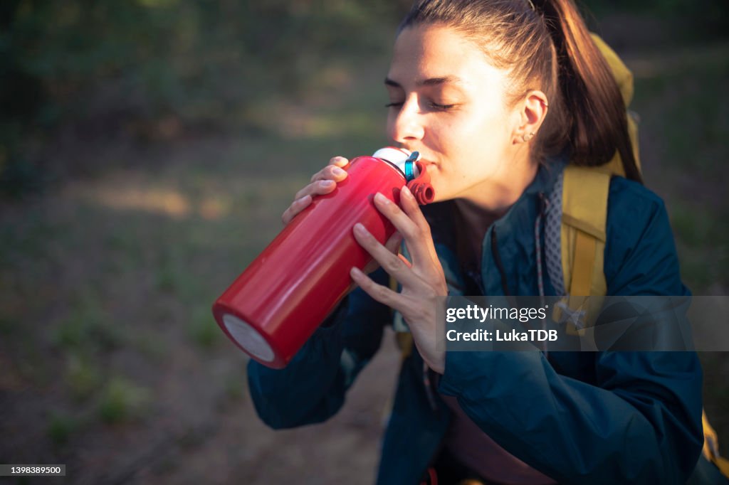 Müde von langen Wanderungen, trinkt die Wanderin Wasser.