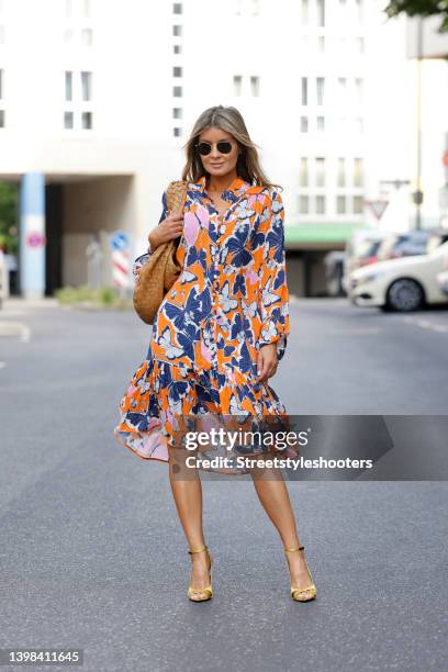 Influencer Gitta Banko wearing a multicolored midi dress with butterfly print by Sem Per Lei, gold and black sandals by Saint Laurent, sunglasses by...