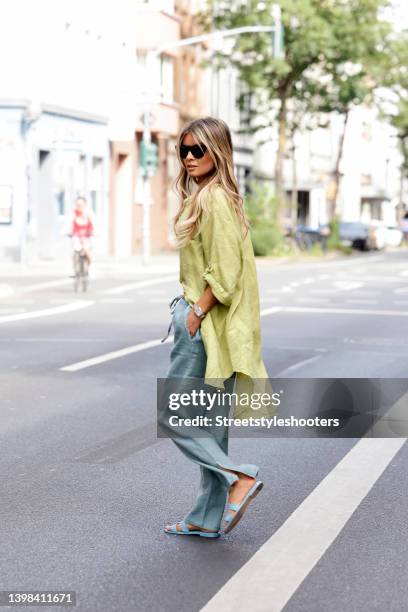 Influencer Gitta Banko wearing a light green linen blouse by Crossley, mint green pants by Crossley, pastel blue sandals by Hermes, a black and beige...