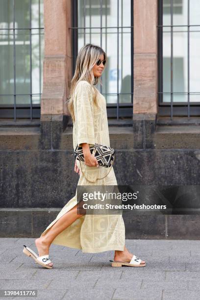 Influencer Gitta Banko wearing a long pale yellow crochet maxi dress by Nanushka, white sandals by Chanel, a black and beige bag by Saint Laurent and...
