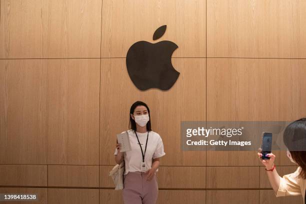 People pose with the Apple logo at the new Apple retail store at Wuhan International Plaza on May 21, 2022 in Wuhan, Hubei Province, China. According...