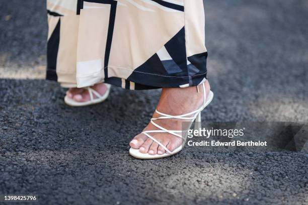 Hannah Romao wears a black / white latte / blue print pattern long dress, white leather strappy heels sandals , on May 20, 2022 in Cannes, France.