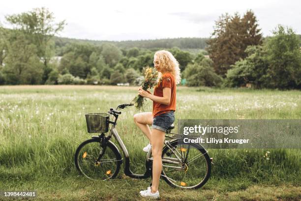 woman walking with bicycle in a field. - may in the summer stock pictures, royalty-free photos & images