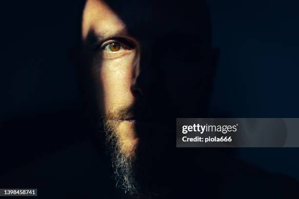 dramatic light portrait: bearded man in the shadow - half beard stock pictures, royalty-free photos & images