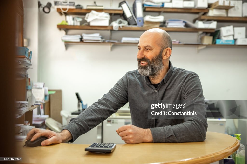 Caucasian man working at the copy shop, while using computer
