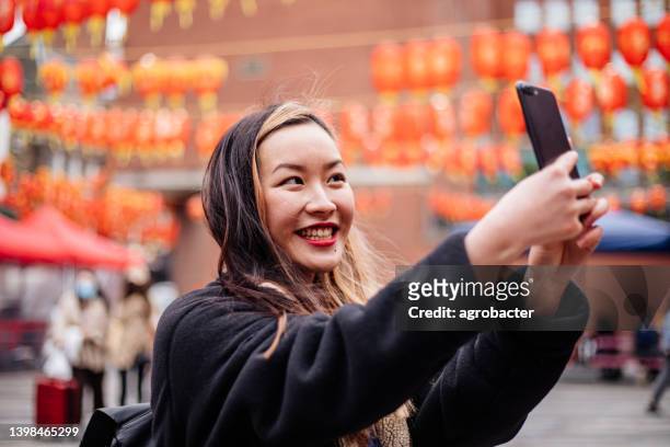 young asian woman using phone at chinatown - chinatown stock pictures, royalty-free photos & images