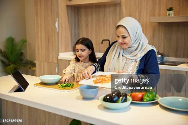 young saudi girl helping grandmother in family kitchen - grandmother stock pictures, royalty-free photos & images