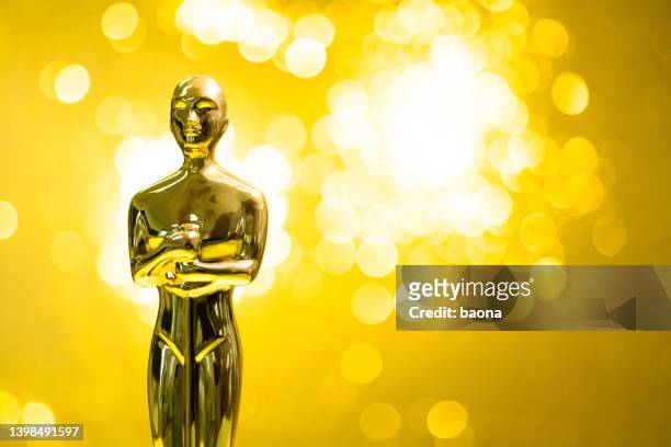 estatuilla dorada sobre fondo amarillo brillante - awards trophies fotografías e imágenes de stock