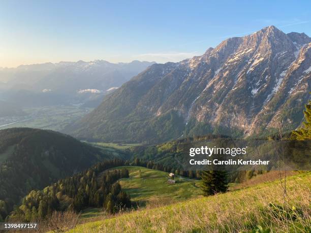 view of mountain massif with mountain hut and green pastures at sunrise | austria - alm hütte stock-fotos und bilder