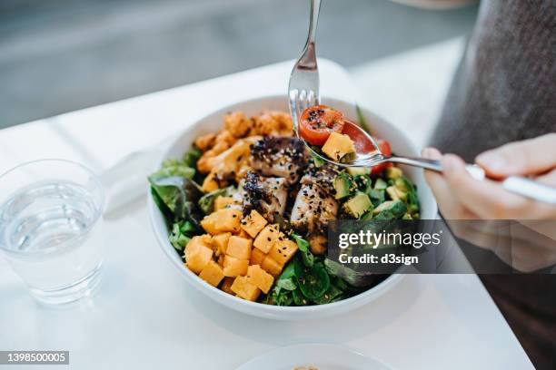 close up, high angle shot of young woman enjoying multi-coloured healthy fruit, vegetables with grilled chicken salad bowl with balanced nutrition in cafe, with a glass of water by the side. healthy eating lifestyle. people, food and lifestyle concept - 健康飲食 個照片及圖片檔