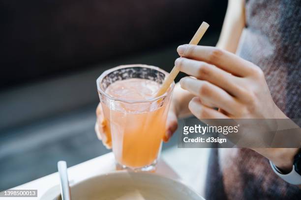 close up shot of young woman drinking a glass of fresh iced pink lemonade with eco-friendly straws during meal in cafe. sustainable lifestyle, eco trend, going green lifestyle - pajita fotografías e imágenes de stock