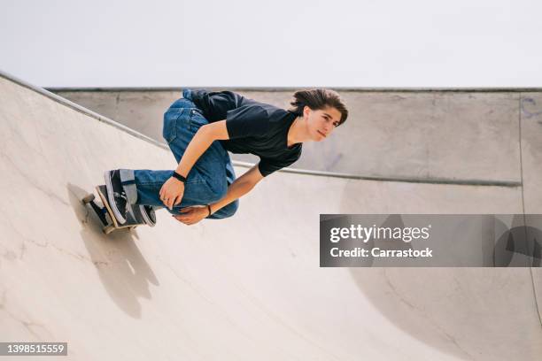 young boy riding skateboard at skatepark - boy skatepark stock-fotos und bilder