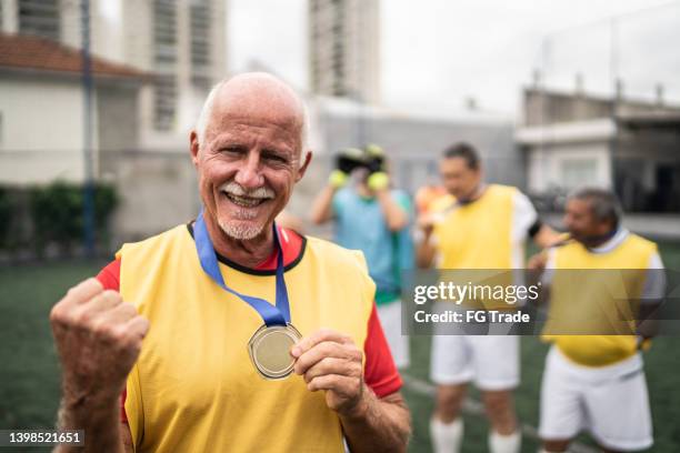 retrato de un hombre mayor sosteniendo la medalla en el campo de fútbol - medal of honor fotografías e imágenes de stock