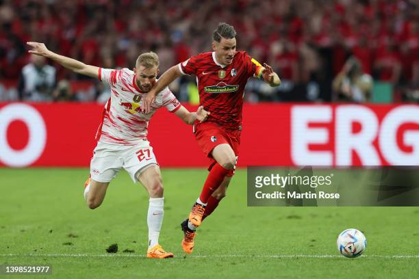 Christian Guenter of SC Freiburg runs with the ball whilst under pressure from Konrad Laimer of RB Leipzig during the final match of the DFB Cup 2022...