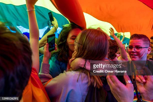 Couple of women kiss under a giant rainbow flag during the pride parade in the centre of the Belgian capital on May 21, 2022 in Brussels, Belgium....
