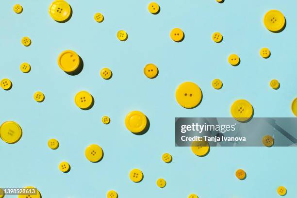 pattern of yellow buttons on blue background - bottone articoli di merceria foto e immagini stock