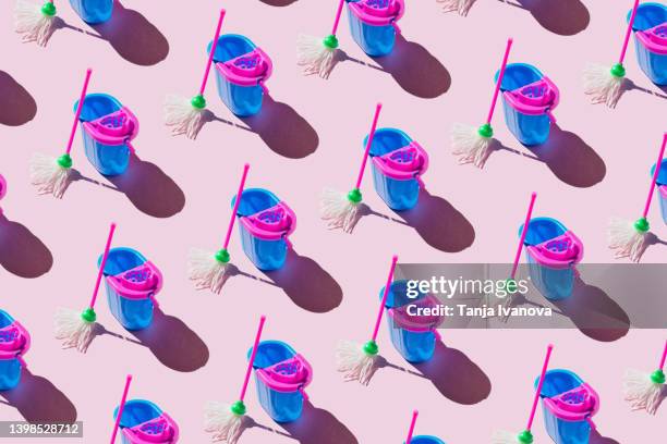 pattern made of buckets and mops on pink background. cleaning service concept - putzeimer stock-fotos und bilder