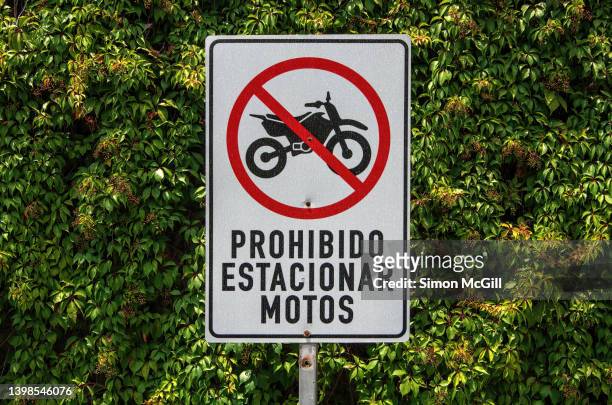 spanish-language sign stating 'prohibido estacionar moto' [motorcycle parking prohibited] on a city street - spanish language stock pictures, royalty-free photos & images