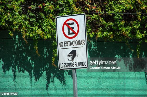 spanish-language sign stating 'no estacionar. los estamos filmando' [no parking. we are filming you] on a city street - filmando stock pictures, royalty-free photos & images