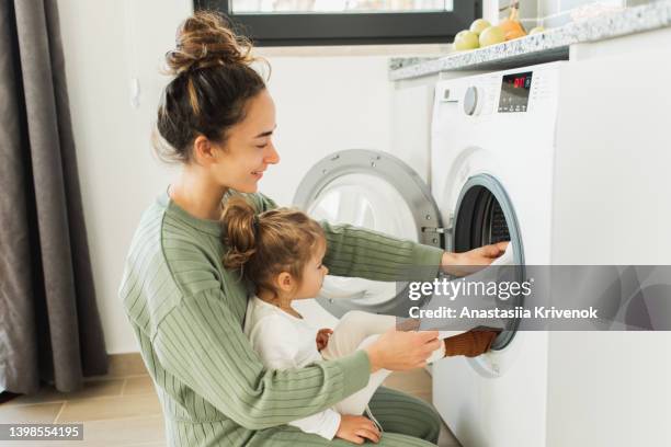 mother and child girl little helper loading washing machine. - washing machine imagens e fotografias de stock