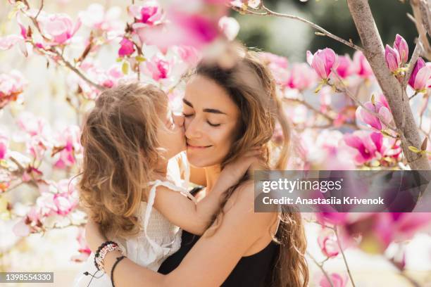 mother and daughter enjoy blooming magnolia trees. - elegance family stock pictures, royalty-free photos & images