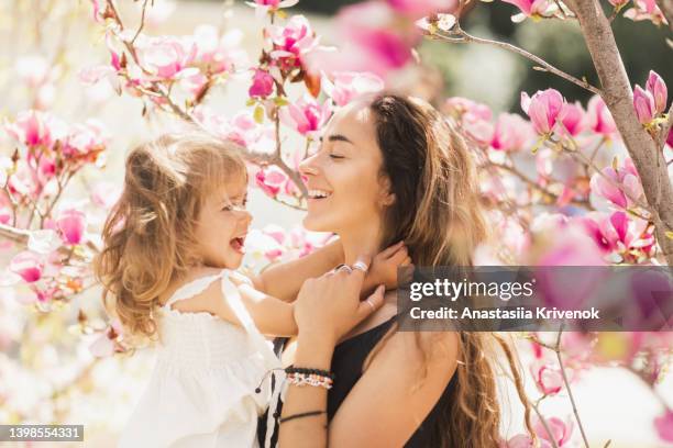 mother and daughter enjoy blooming magnolia trees. - magnolia stock-fotos und bilder