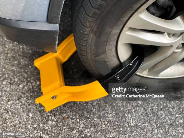 wheel clamp: bright orange immobilization device on front car wheel - parkkralle stock-fotos und bilder