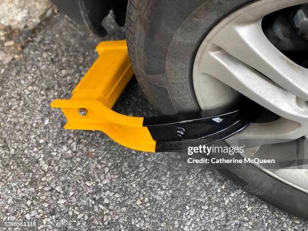 wheel clamp: bright orange immobilization device on front car wheel - department of motor vehicles stock pictures, royalty-free photos & images