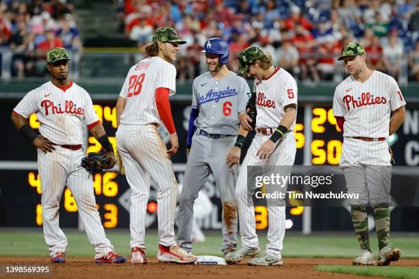 Trea Turner of the Los Angeles Dodgers speaks with Alec Bohm and Bryson Stott of the Philadelphia Phillies during the seventh inning at Citizens Bank...