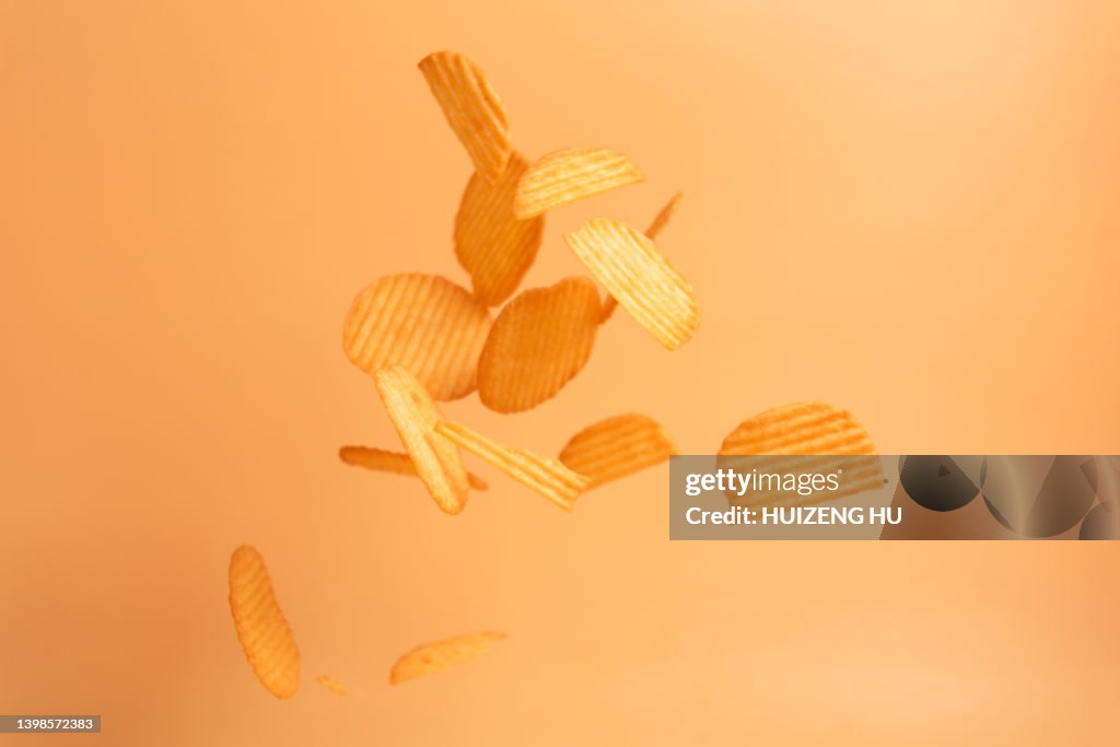 Flying potato chips on yellow background. concept