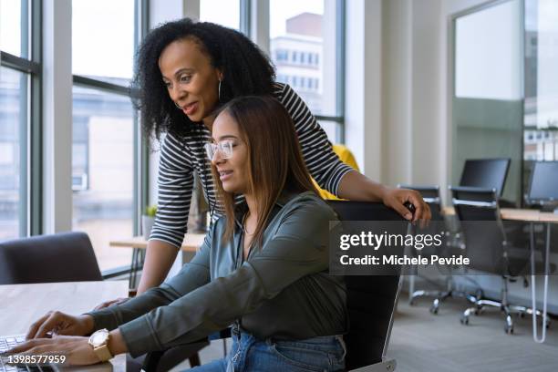 donna che fa da mentore a un giovane dipendente in ufficio - mentoring foto e immagini stock