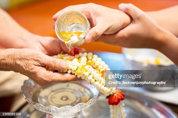 hands pouring scented water onto elder hands in songkran festival, thai traditional new year's day. - songkran stock pictures, royalty-free photos & images