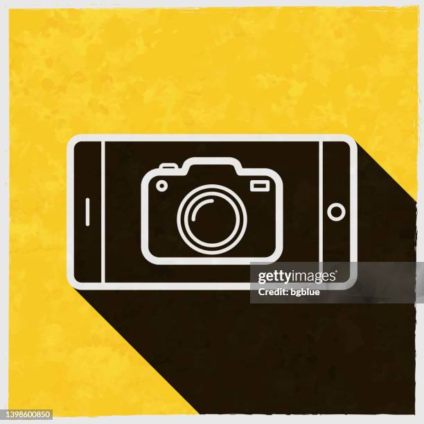 smartphone with camera. icon with long shadow on textured yellow background - iphone camera stock illustrations