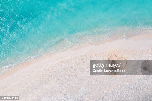 romantic love concept from aerial view. cute loving heart shape drawn in sand on beach. honeymoon and couple travel concept, copy space - coeur symbole dune idée photos et images de collection
