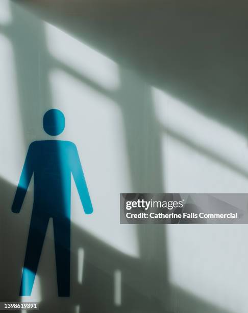 traditional, simple, internationally recognised symbol for male on a wall, illuminated by streams of light - handicap photos et images de collection