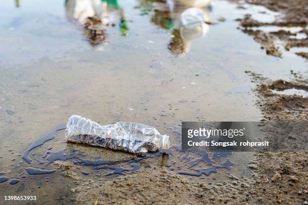 toxic liquid and crushed plastic bottles polluting water - oil slick stock pictures, royalty-free photos & images