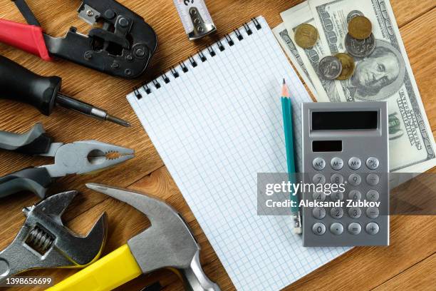 tools for building a house or repairing an apartment, on a wooden background or table. workplace of the foreman. the theme of home and professional repair and construction. notepad and pen, calculator and cash dollars. copy space. - service level high stock pictures, royalty-free photos & images