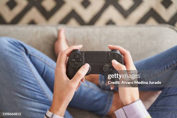 young woman in casual clothes playing video games in her living room. - control room stockfoto's en -beelden