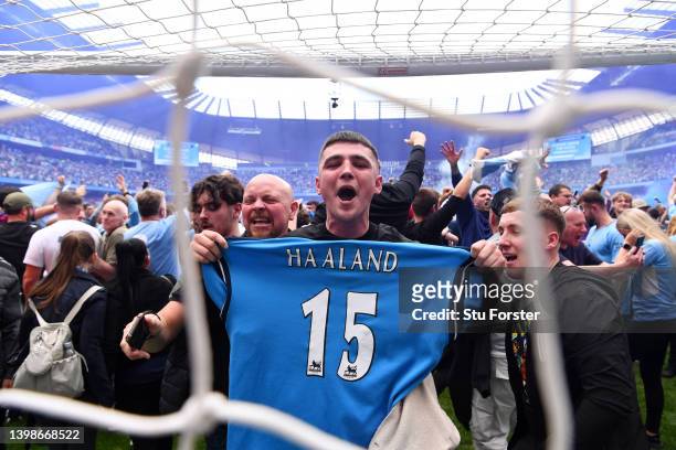 Manchester City fan holding a Manchester City shirt with their new signing Erling Haaland on the back celebrates on the pitch after their side...