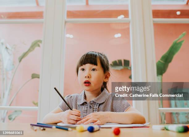 a cute little chinese girl does homework at a table - concept does not exist 個照片及圖片檔