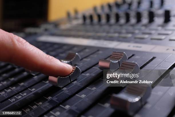 amplifying equipment. the man's hands switch and rearrange the handles of the studio audio mixer and faders. workplace and equipment of the sound engineer. acoustic music mixing, selective focus. - radio dj stockfoto's en -beelden