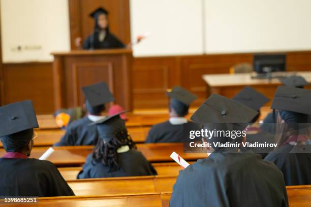 a student is having a speech about the graduation in front of the auditorium - graduation speech stock pictures, royalty-free photos & images